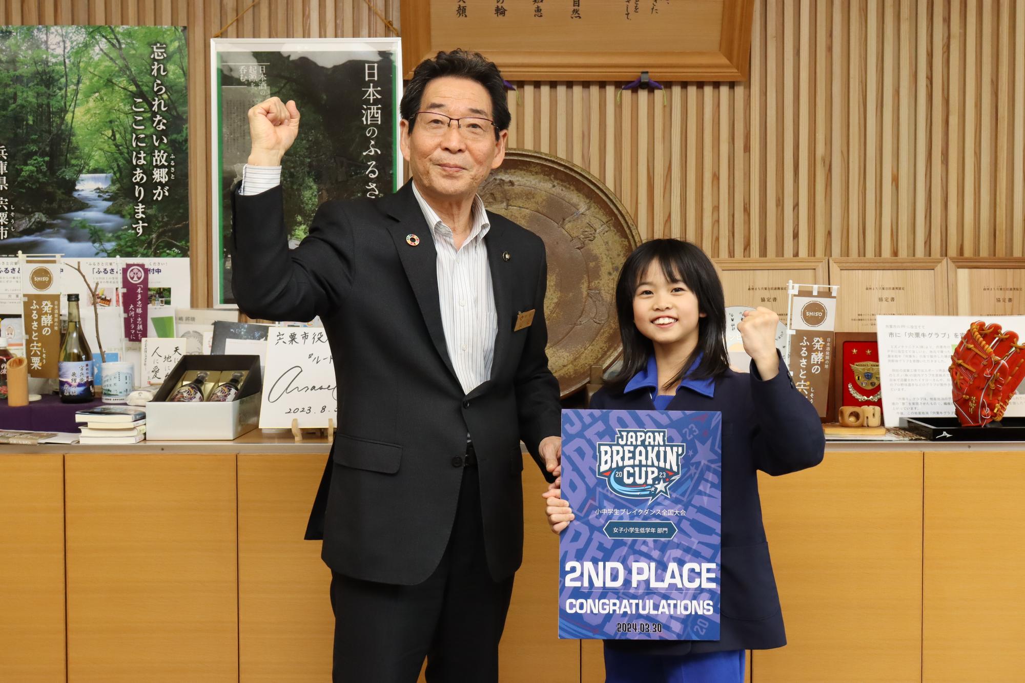 宇田朱々菜さんと並んで2人でガッツポーズしている福元市長の写真