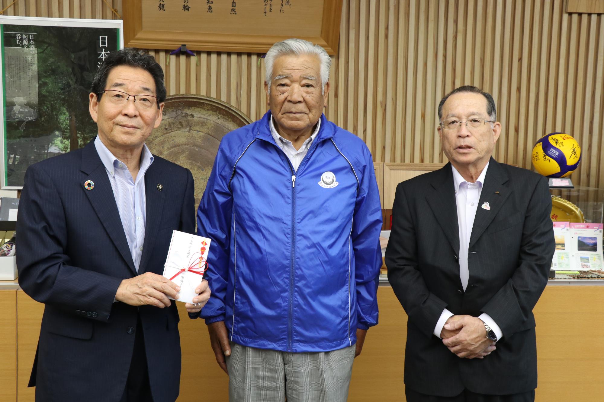 福元市長が受け取った寄付目録を手に宍粟市ゴルフ協会の皆さんと並んでいる写真