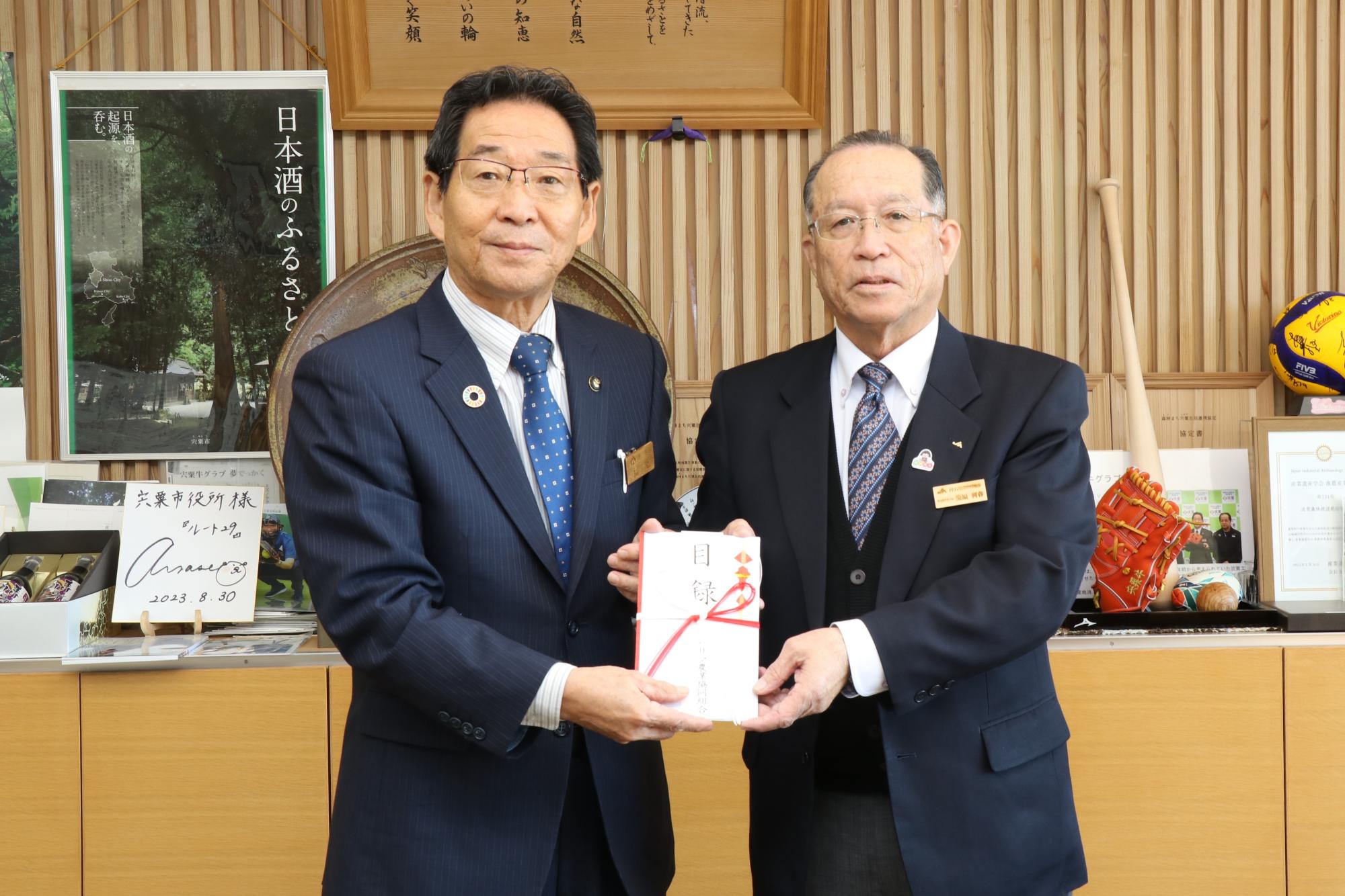 JAハリマ組合長の柴原さんと福元市長が寄付金目録を両側からもって正面を向いている写真