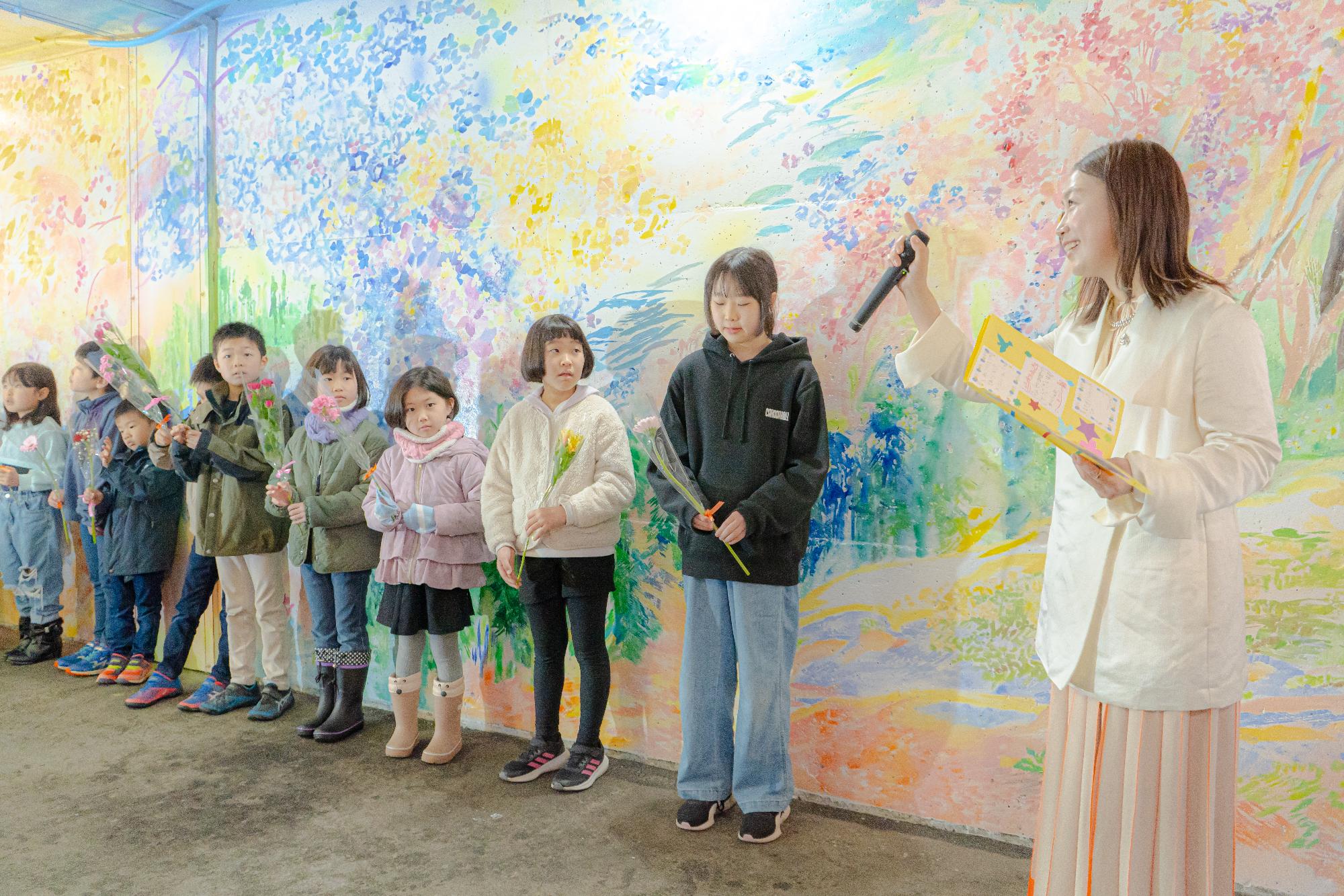 シソラミチお披露目会で美術作家の植田志保さんの話を聞く参加者らの写真