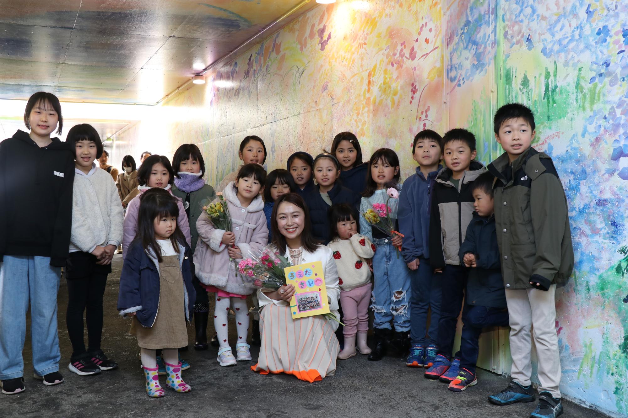 シソラミチお披露目会で美術作家の植田志保さんを囲んで子どもたちが並んでいる写真