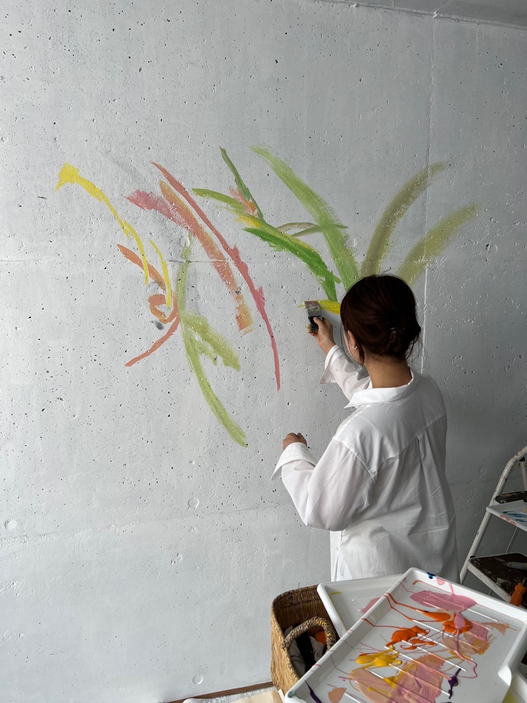 山崎インター歩行者通路リニューアル事業で通路壁面に美術作家の植田さんが色を塗り始めたところを後ろから撮影した写真