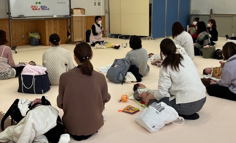 助産師よりベビーマッサージの話を聞く赤ちゃんのお母さんたちの写真
